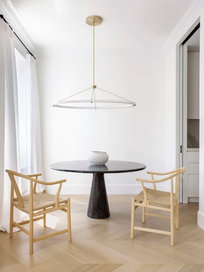 Mesa de comedor de mármol firmada por Angelo Mangiarotti. Sillas ‘China’ de Hans J. Wegner (todo Suite NY), lámpara ‘Halo’ de Paul Loebach para Roll & Hill.