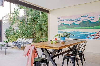 Mesa de lapacho (Crudo Home) rodeada de sillas ‘Tólix’. Mural realizado por Michel Fassi (Eileen Vergez, asesoramiento de arte).