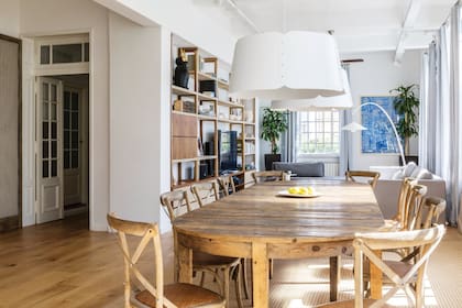 Mesa de madera con el detalle de sus cabeceras curvas y sillas tipo Thonet de Mercado de Pulgas iluminadas por lámparas ‘Gajo’ (La Feliz), de inspiración fabril.
