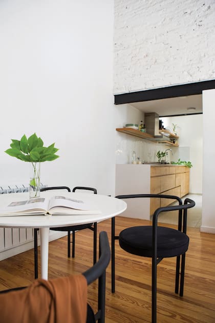 Mesa estilo Tulip con cuatro sillas ‘R’ (Rahola). Todo el largo de la cocina cuenta con espacio de guardado.