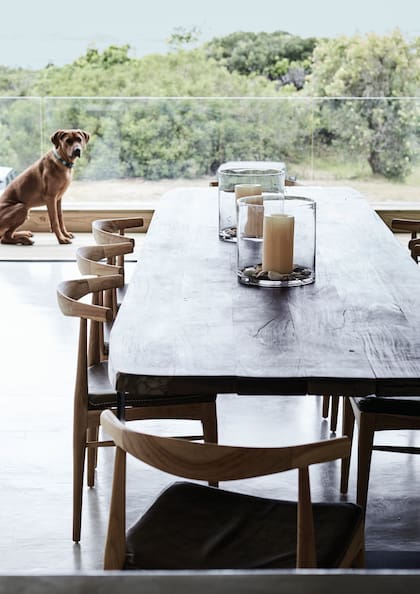 Mesa hecha a medida a partir de un tablón de madera recuperada acompañada por sillas de diseño escandinavo