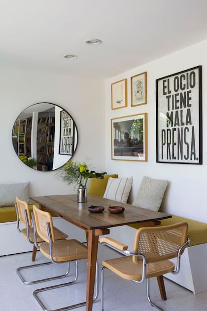 Mesa (La Base Estudio) con sillas ‘Cesca’ (Michael Thonet). Bancos de obra con colchonetas (Sillones Europea). Foto tomada por Cecilia Espinosa, afiche de Mala Prensa y cuadro bordado de Caro Malbrán