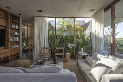 Mesa ratona con tapa de mármol de Carrara y sofás (todo de Milanese Sofá & Deco). Dúo de sillas con apoyabrazos (Navarro Hábitat). Cortinas (Patricia López).