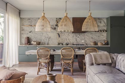 Mesada, alzada y mesa/isla en granito ‘Alpinus’ (Canteras del Mundo) trabajado por Marmolería Ragomar. Campana con acabado óxido (Compañía Nativa Estudio). Muebles de cocina en melamina ‘Safari’ de Faplac.