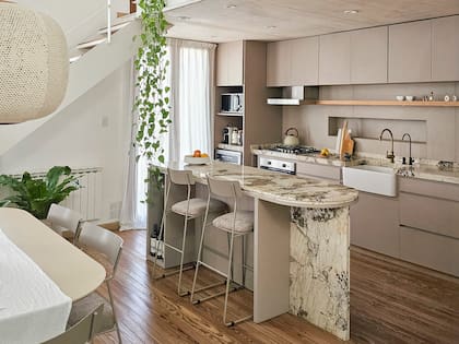Mesada de piedra natural (Alpinus). Mueble de cocina diseñado por el estudio, melamina Sahara (Faplac) y estante enchapado en Paraíso. Banquetas (La carpintería muebles).