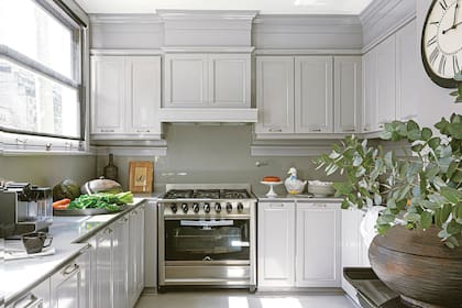 Mesadas y alzadas de Silestone, que limita con una moldura de madera, todo en el mismo tono. El piso de madera original se cambió por un porcelanato (SBG), y la campana se ocultó siguiendo el diseño y el gris ‘Despeñadero’ (Alba) de los muebles.