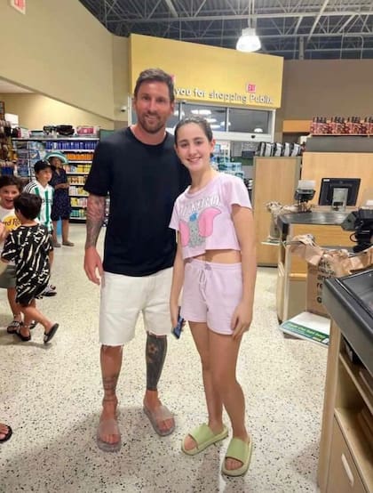 Messi con una fan en el supermercado y, a la izquierda, se puede ver a sus hijos jugando