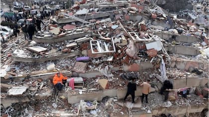 Mesut Hancer, en el centro con un abrigo naranja, en medio de las ruinas del que fue su edificio