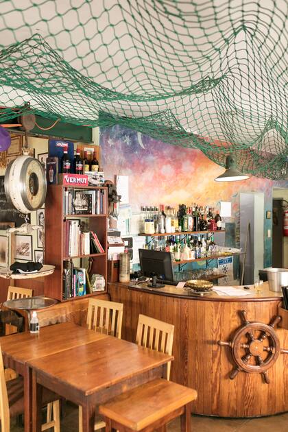 Mezcla de bodegón tradicional y cantina moderna, el salón está decorado con redes que cuelgan, timones de madera, balanzas y carteles viejos.