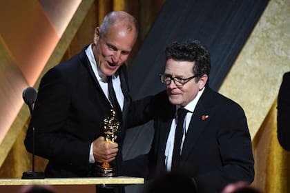 Michael J. Fox recibe el premio de manos de Woody Harrelson.