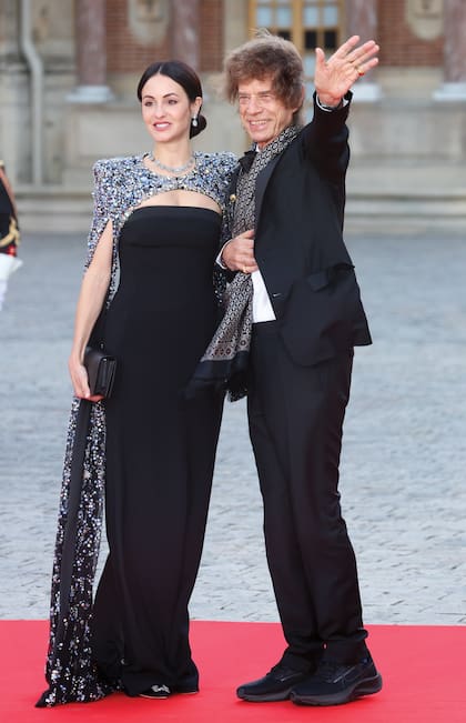 Mick Jagger y Melanie Hamrick hacen su arribo al banquete. La Pareja del cantante llevó un strapless de corte sirena, acompañado por una capa bordada en pedrería multicolor.