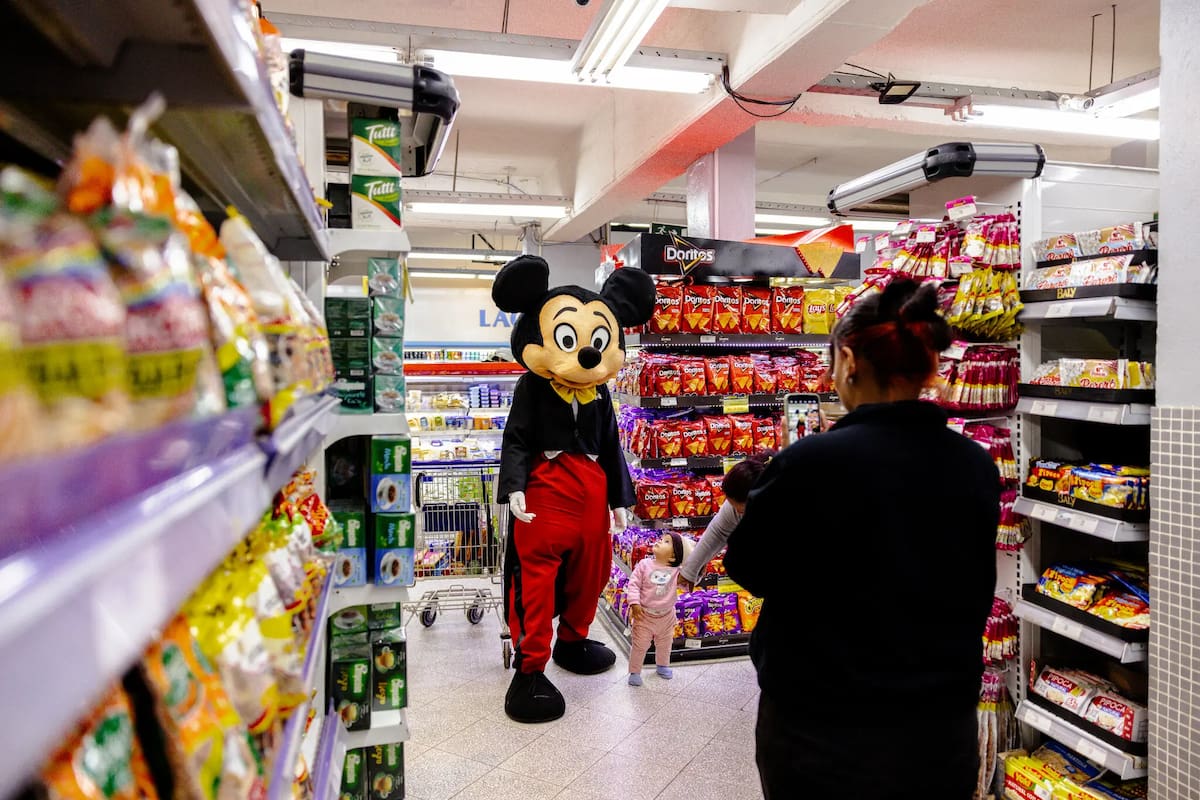 Mickey, la popular mascota de una empresa paraguaya, saluda a las familias, se hace fotos y reparte muestras de comida en una tienda de comestibles de Luque, Paraguay