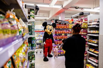 Mickey, la popular mascota de una empresa paraguaya, saluda a las familias, se hace fotos y reparte muestras de comida en una tienda de comestibles de Luque, Paraguay