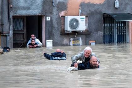Miembros de la gendarmería nacional de Italia llevan a los residentes a cuestas por las calles inundadas