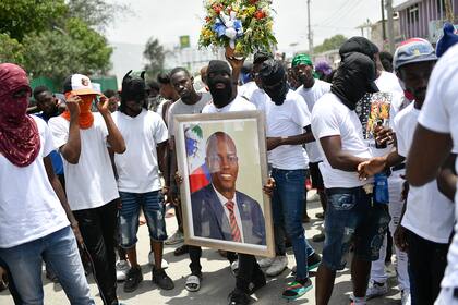 Miembros de una pandilla encabezada por Jimmy Cherizier, alias Berbecue, un expolicía que encabeza una coalición de pandillas llamada "Familia G9", transportan un retrato del asesinado presidente Jovenel Moise durante una marcha
