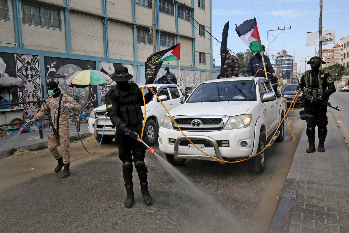 Miembros del ala armada de la Jihad Islámica palestina, las Brigadas Al-Quds, rocían desinfectante en las calles de Rafah, en el sur de la Franja de Gaza como parte de la campaña contra el coronavirus