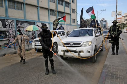 Miembros del ala armada de la Jihad Islámica palestina, las Brigadas Al-Quds, rocían desinfectante en las calles de Rafah, en el sur de la Franja de Gaza como parte de la campaña contra el coronavirus