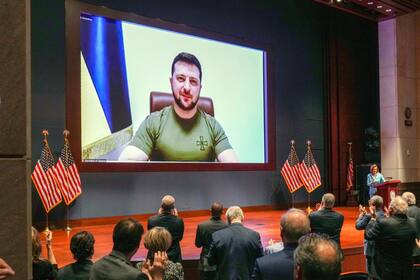 Miembros del Congreso estadounidense aplauden de pie al presidente ucraniano Volodymyr Zelensky antes de que les dirija un discurso virtual en un auditorio en el Capitolio en Washington