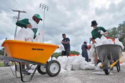 Miembros del departamento de parques y jardines de Tampa, Florida, ayuda a los residentes con costales de arena antes de la llegada de la tormenta Idalia, el 28 de agosto de 2023, en Tampa, Florida. (AP Foto/Chris O'Meara)