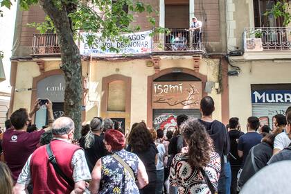 Miembros del sindicato de la vivienda y los vecinos celebran la cancelación de la orden de desalojo con una familia en un balcón.
