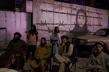 Miembros talibanes sentados frente a un mural que representa a una mujer detrás de un alambre de púas en Kabul, Afganistán, el martes 21 de septiembre de 2021.
El lunes, los talibanes prohibieron a las barberías de una provincia del sur de Afganistán el afeitado o el recorte de la barba, alegando que su edicto está en consonancia con la sharía, o ley religiosa del islam. (AP Foto/Felipe Dana)