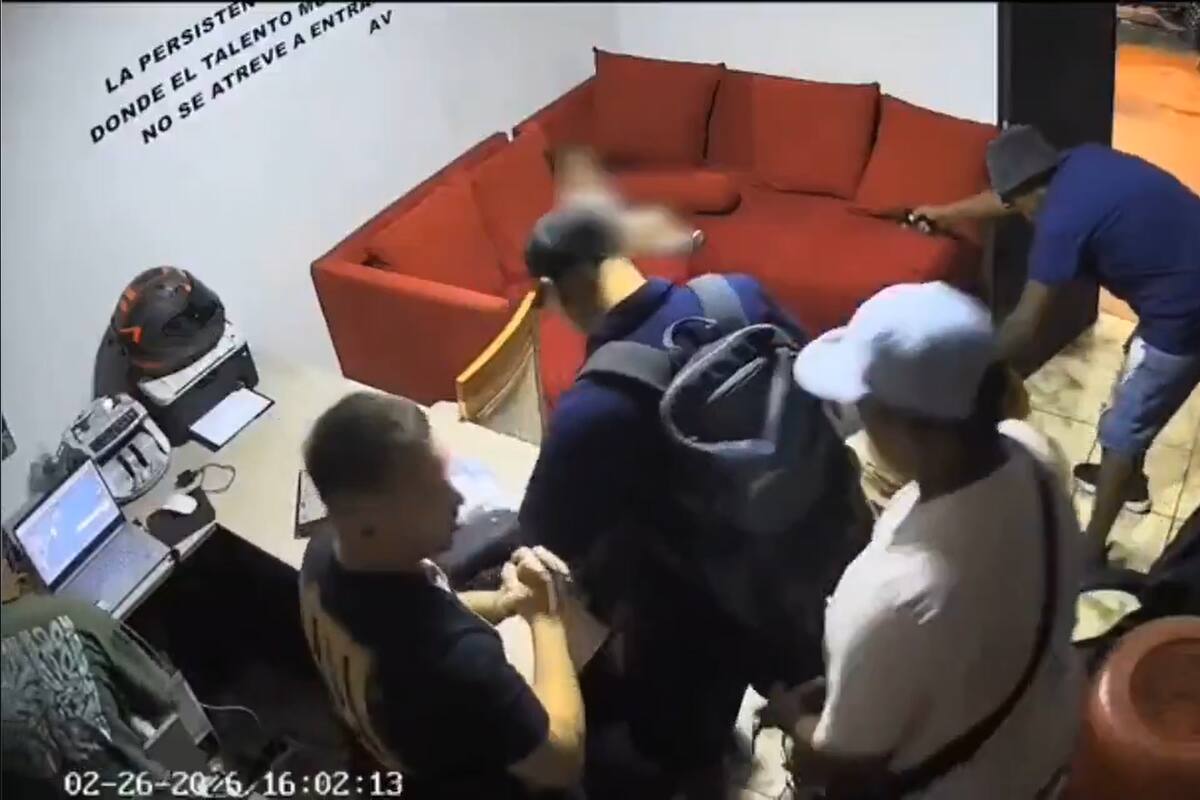 Mientras los asaltantes hurgan los cajones y bolsos de la oficina, uno de ellos apunta contra la bebé sentada en el sillón