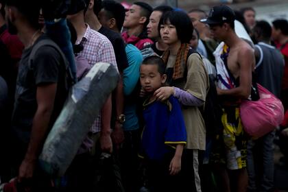 Migrantes chinos hacen fila para abordar una embarcación hacia Lajas Blancas después de cruzar a pie la selva del Darién, el domingo 7 de mayo de 2023, en Bajo Chiquito, Panamá. (AP Foto/Natacha Pisarenko)