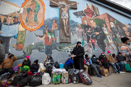 Migrantes comen y esperan ayuda, acampados en una calle del centro de El Paso, Texas, 18 de diciembre de 2022. (AP Foto/Andres Leighton)
