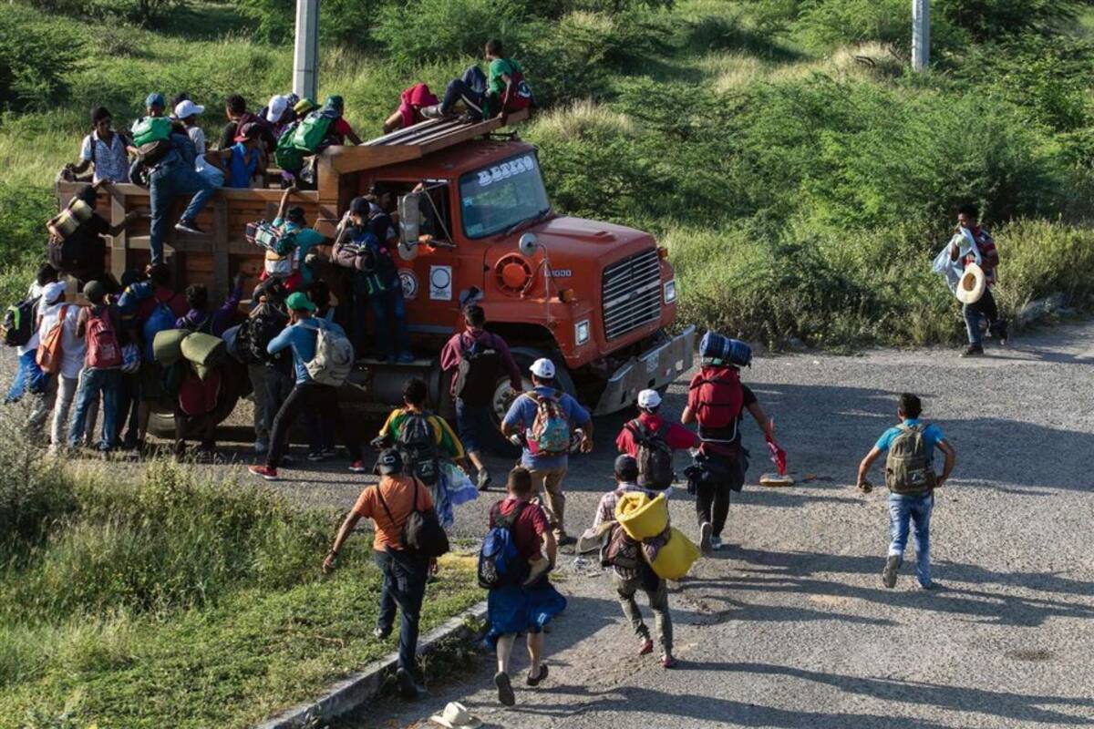 Migrantes de la caravana de hondureños rumbo a Estados Unidos trepan a un camión en Oaxaca, México