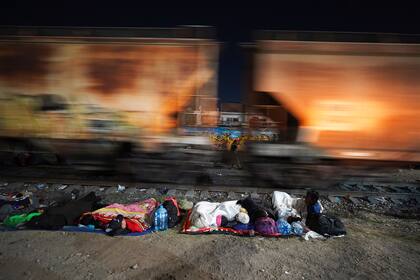Migrantes duermen junto a las vías mientras esperan a un tren hacia el norte que se detenga tiempo suficiente para subir, en Irapuato, México, el viernes 22 de septiembre de 2023. (AP Foto/Marco Ugarte)