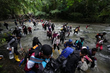 Migrantes, en su mayoría venezolanos, cruzan un río en la selva del Darién el 15 de octubre de 2022.