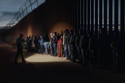 Migrantes esperan a ser procesados por las autoridades de Estados Unidos después de cruzar la frontera, en diciembre de 2023
