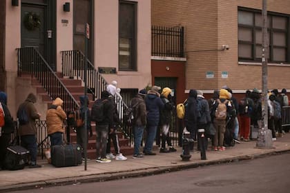 Migrantes esperan en el frío para encontrar refugio fuera del centro de asistencia en la escuela primaria St. Brigid, el 5 de diciembre de 2023, en Nueva York