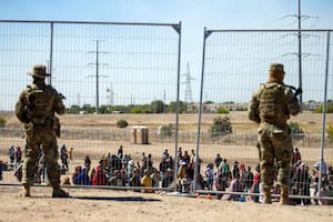 Migrantes esperan junto a una valla fronteriza bajo la vigilancia de la Guardia Nacional de Texas, Estados Unidos, el 10 de mayo de 2023
