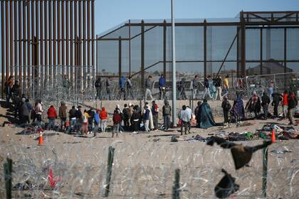 Migrantes formados después de ser detenidos por las autoridades migratorias de Estados Unidos en el muro fronterizo, en una imagen captada desde Ciudad Juárez, México. (AP Foto/Christian Chavez)