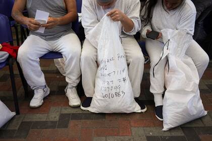 Migrantes guatemaltecos deportados de Estados Unidos revisan sus pertenencias tras aterrizar en Ciudad de Guatemala, el 27 de diciembre de 2024