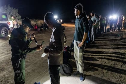 Migrantes hacen fila para ser procesados por la Patrulla Fronteriza tras cruzar a Estados Unidos desde México, en Jacumba Hot Springs (California)