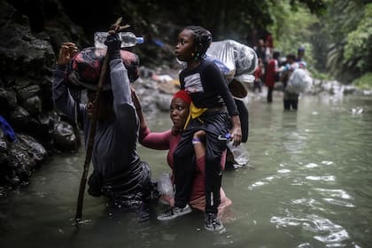 Migrantes haitianos caminan por el agua mientras cruzan el Tapón del Darién, de Colombia a Panamá con la esperanza de llegar a EEUU, el 9 de mayo de 2023. Cada vez más, cientos de miles de migrantes se arriesgan a la peligrosa travesía por la selva. (Foto AP/Iván Valencia, Archivo)