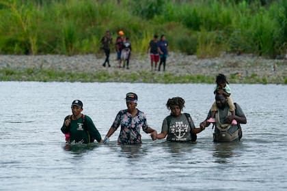 Migrantes haitianos vadean el río Tuquesa después de caminar por el Tapón del Darién, el miércoles 4 de octubre de 2023, en Bajo Chiquito, Panamá (AP Foto/Arnulfo Franco, Archivo)