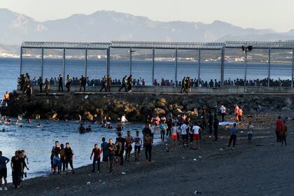 Migrantes nadan y caminan hacia el enclave español de Ceuta, en la costa africana, tras cruzar la frontera desde Marruecos, el 17 de mayo de 2021. (Antonio Sempere/Europa Press via AP)