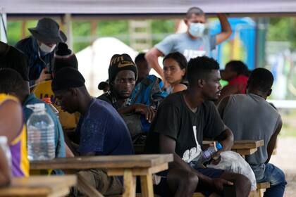 Migrantes se reúnen en un campamento luego de una visita de las cancilleres de Panamá y Colombia en San Vicente, provincia de Darién, Panamá, cerca de la frontera con Colombia, el viernes 6 de agosto de 2021.. (AP Foto/Arnulfo Franco)