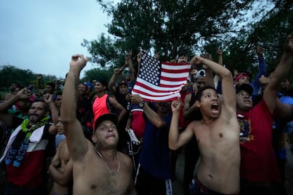 Migrantes venezolanos ondean una bandera estadounidense hacia un helicóptero de televisión que sobrevuela la zona junto al río Bravo (Grande) en Matamoros, México, el viernes 12 de mayo de 2023, un día después de que se retiraron las restricciones al asilo implementadas en la pandemia de coronavirus, conocidas como Título 42. La imagen fue parte de una serie tomada por los fotógrafos de The Associated Press Iván Valencia, Eduardo Verdugo, Félix Márquez, Marco Ugarte, Fernando Llano, Eric Gay, Gregory Bull y Christian Chávez que ganó el Premio Pulitzer 2024 en Fotografía de Reportaje. (AP Foto/Fernando Llano)