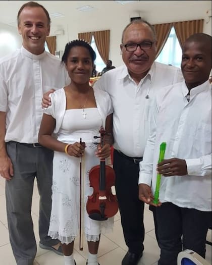 El padre Miguel y chicos de la orquesta junto al presidente de Nueva Guinea, que apoya la iniciativa de los curas