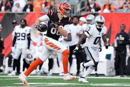Mike Gesicki, izquierda, tight end de los Bengals de Cincinnati, corre con el balón ante la mirada de Jakorian Bennett (0), cornerback de los Raiders de Las Vegas, durante la segunda mitad del juego de la NFL, el domingo 3 de noviembre de 2024, en Cincinnati. (AP Foto/Jeff Dean)