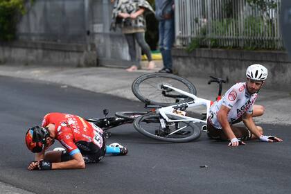 Mikel Landa (izquierda) fracturado en el piso a raíz de un accidente de un tercero, el ciclista estaounidense Joe Dombrowski, con un asistente del Giro de Italia.