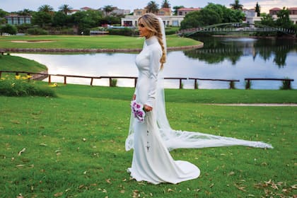Milagros, posando en Sofitel Cardales, con el vestido que Gabriel Lage creó especialmente para ella: un diseño al cuerpo en crêpe marroquí blanco nácar. Tanto los puños como el cuello llevaban bordados geométricos. El velo estaba realizado íntegramente con una técnica artesanal. El detalle: la diadema de cristales checos, tallada en cera de modelado y acabado en metal, realizado por Roxana Zarecki. Lage, que fue el autor del outfit que Mili eligió para el civil, fue quien sugirió el ramo.