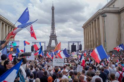 Miles de manifestantes de reúnen el sábado 24 de julio de 2021 en la Plaza del Trocadero, cerca de la Torre Eiffel, para oponerse a la vacunación obligatoria y otras medidas contra el COVID-19, en París. (AP Foto/Rafael Yaghobzadeh)