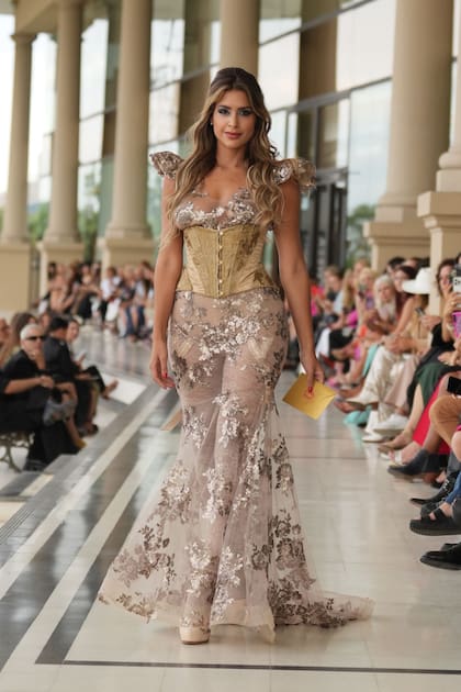 Milett desfiló con un vestido largo con corset dorado y falda con transparencias y flores. “Me encanta la pasarela”, dijo.
