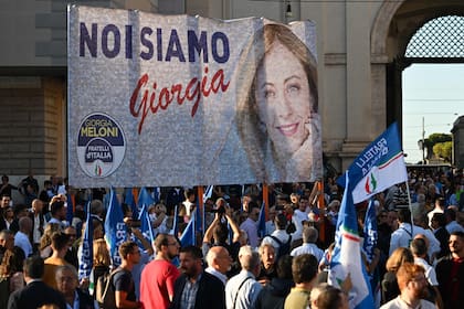 Militantes sostienen el 22 de septiembre de 2022 un cartel de campaña de la líder de Fratelli d'Italia, Giorgia Meloni, antes de un mitin conjunto de los partidos de derecha italianos Hermanos de Italia (Fratelli d'Italia, FdI), la Liga (Lega) y Forza Italia en la Piazza del Popolo en Roma, antes de las elecciones generales del 25 de septiembre.
