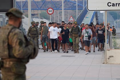 Militares españoles escoltan a migrantes que cruzaron a España de regreso a Marruecos desde el enclave español de Ceuta, el sábado 1 de agosto de 2026